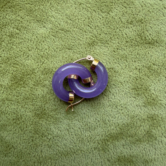 Lavender jade hoops with 14k gold metal accents, placed on a textured olive green fabric background.