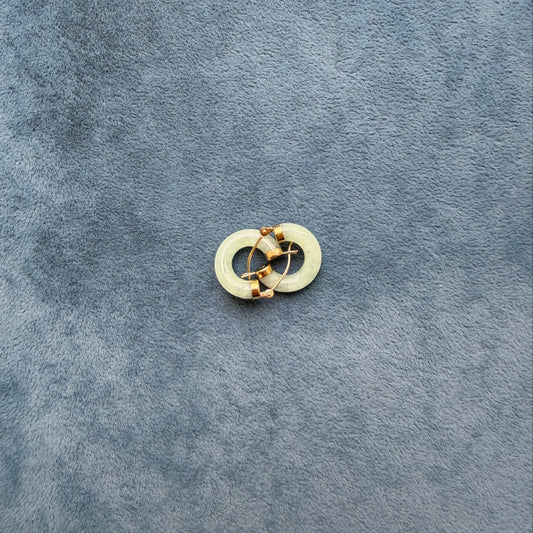 A small light green jade hoop, photographed on a textured dark blue-gray surface.