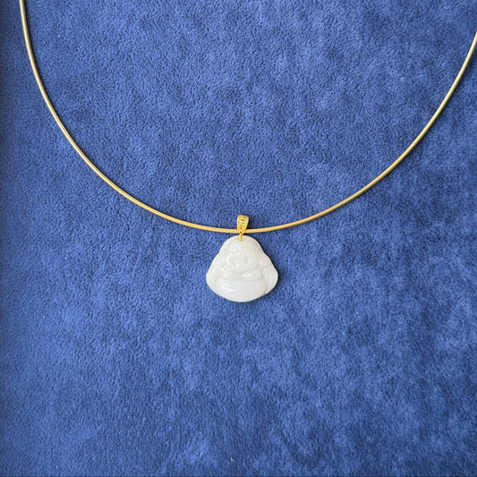 A delicate gold necklace with a small, white jade buddha pendant, displayed on a textured blue velvet jewelry box insert.