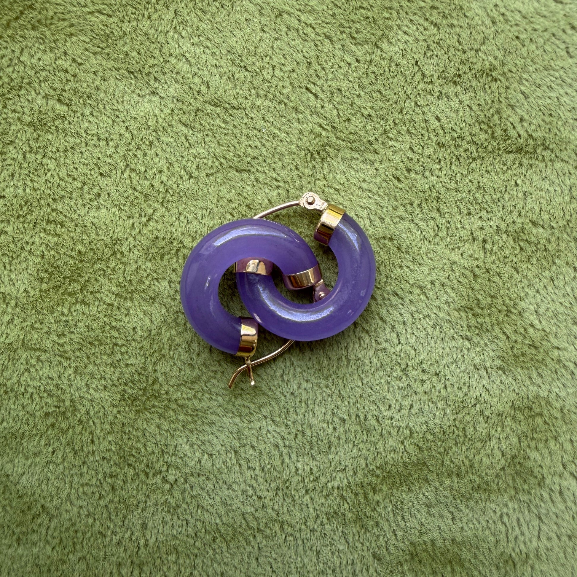 Lavender jade hoops with 14k gold metal accents, placed on a textured olive green fabric background.
