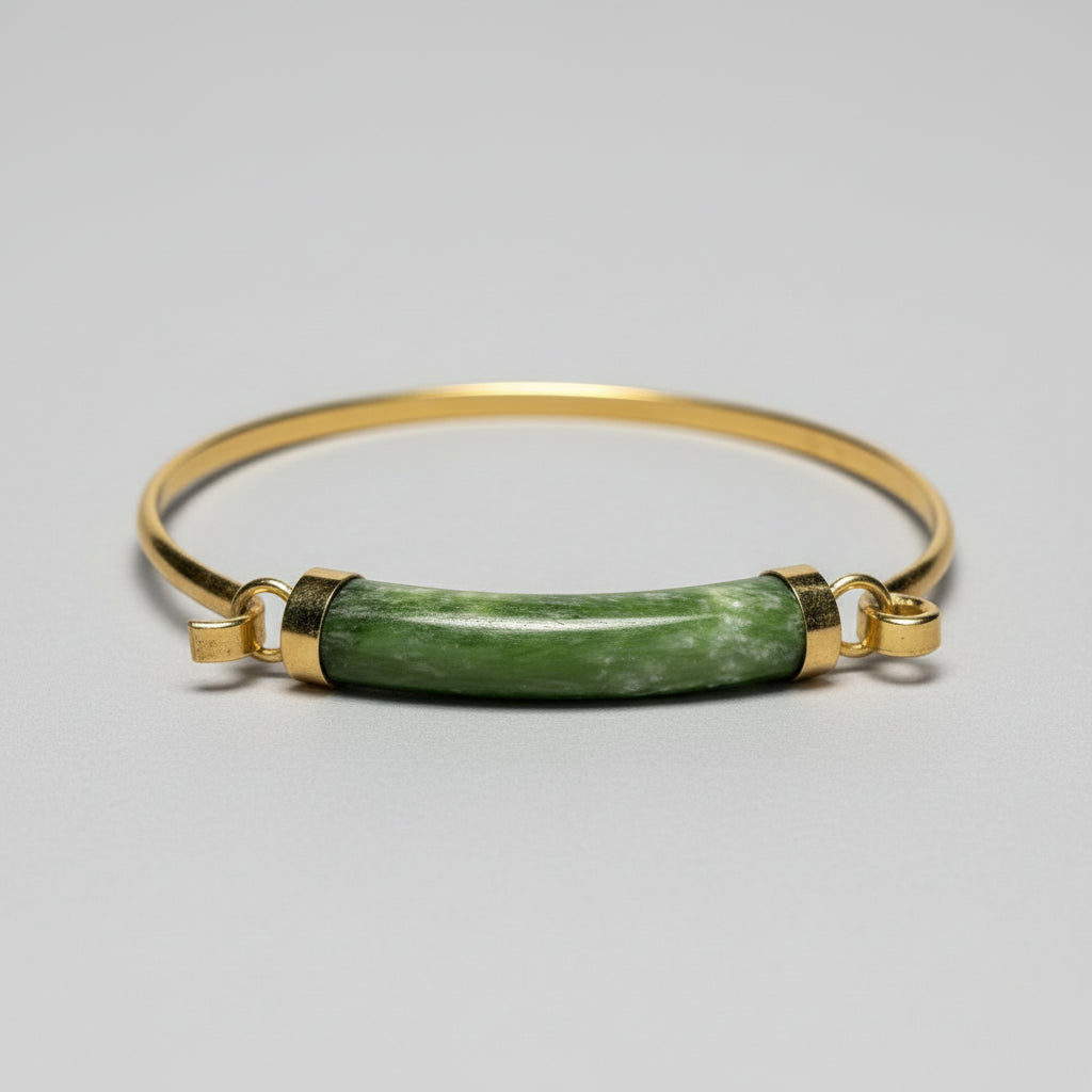 A vintage 1970s gold tension cuff bracelet with a green jade centerpiece and gold-plated design.