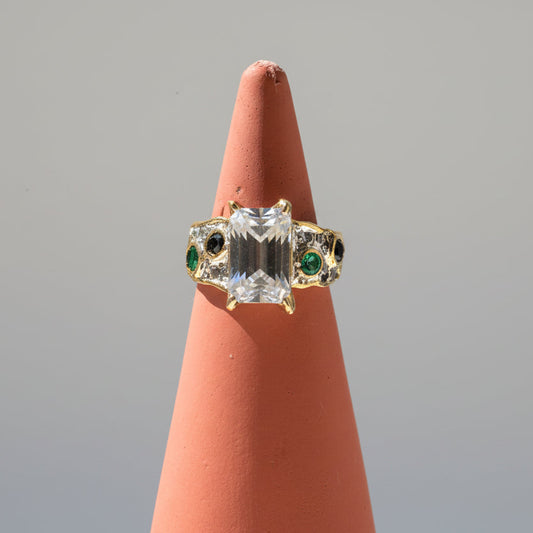 Emerald-cut aquamarine, emerald, and sapphire ring in silver with brass accents.