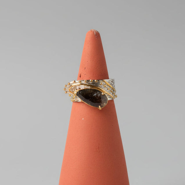 Pear-shaped black rutilated quartz ring set in silver with warm brass accents.