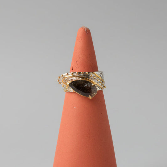 Pear-shaped black rutilated quartz ring set in silver with warm brass accents.