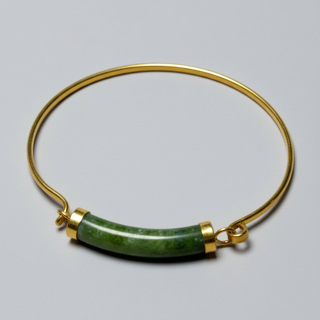 A vintage 1970s gold tension cuff bracelet with a green jade centerpiece and gold-plated design.